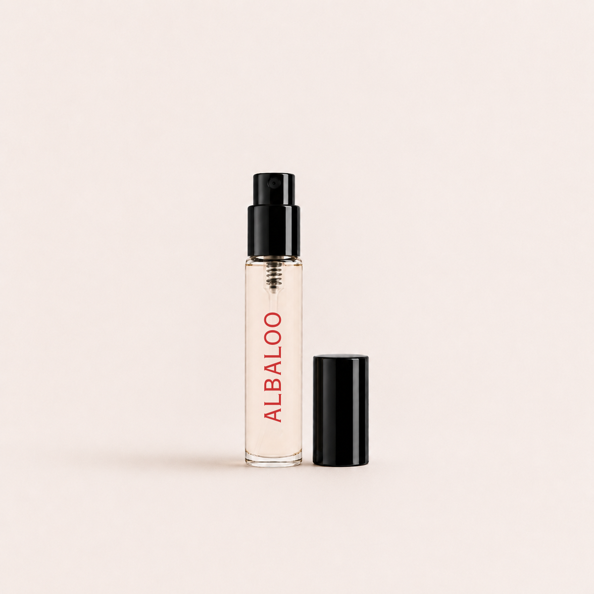 A clear glass perfume atomizer spray bottle with a black spray cap and a separate black cap placed beside it, featuring the brand name 'ALBALOO' printed vertically in red on the bottle. The product is set against a solid, warm off-white background.